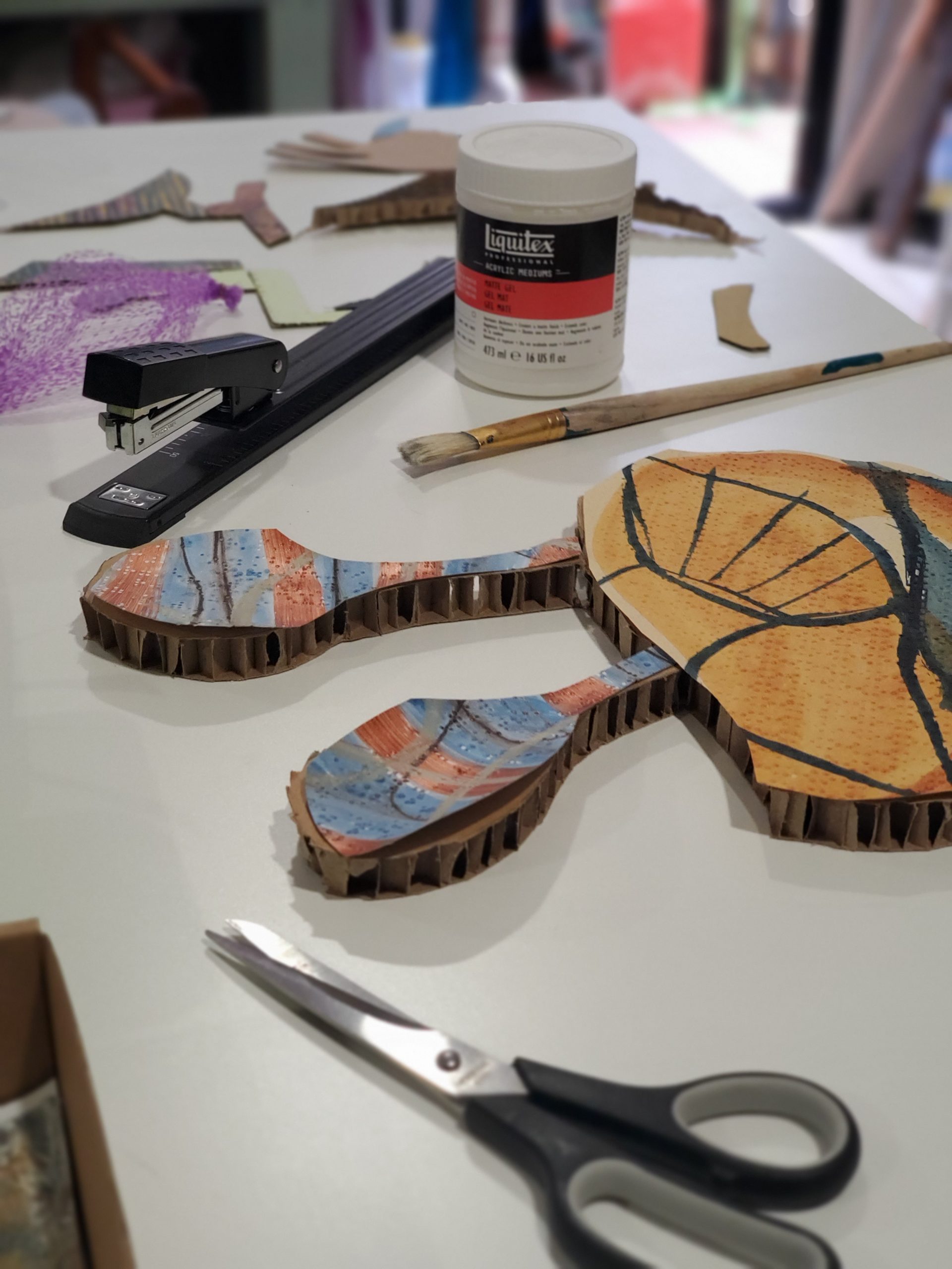 Staples, scissors, glue, and chopped carboard on studio desk.